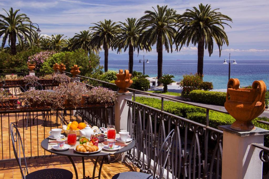 una mesa con comida en el balcón con vistas al océano en Hotel Miramare, en Noli