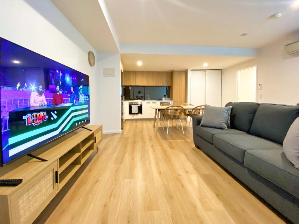 uma sala de estar com um sofá e uma televisão grande em Stunning 2BR Apt @ Adelaide CBD with Pool-Gym-BBQ em Adelaide