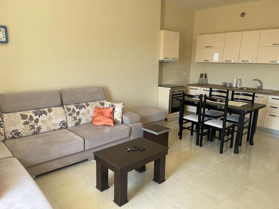 a living room with a couch and a table and a kitchen at Kea_Apartment_Lushnjë in Lushnjë