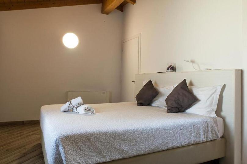 1 dormitorio con 1 cama grande con sábanas y almohadas blancas en BHL SUITE Jacuzzi LEGNANO, en Legnano