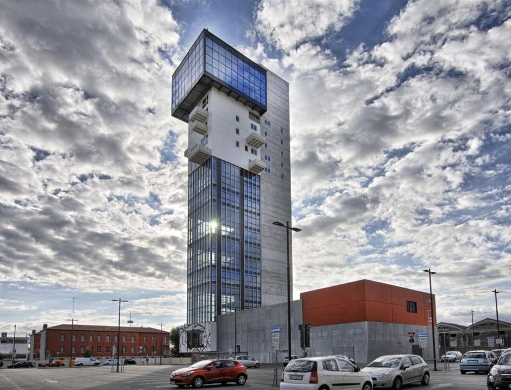 a tall building with cars parked in a parking lot at HTM Venice Suite in Mestre