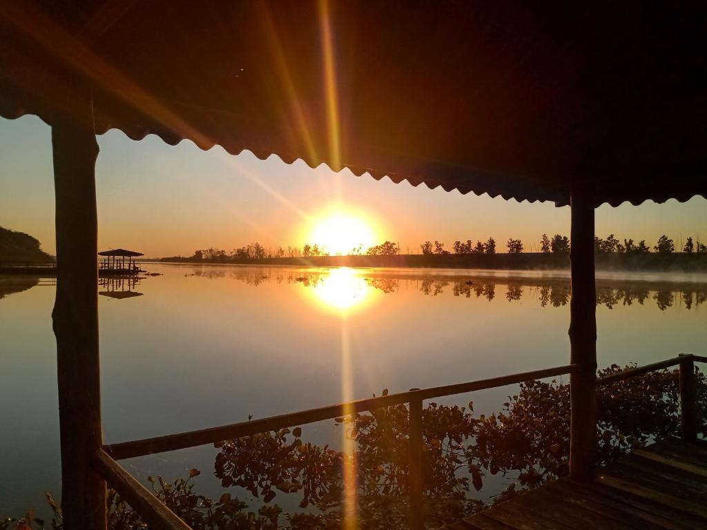 a view of the sun setting over a lake at Rancho Rio Dourado, um paraíso! in Promissão