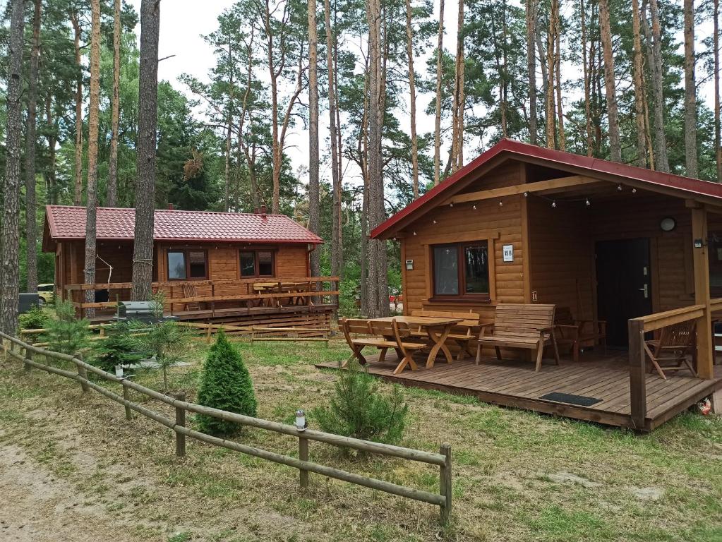 een blokhut met een houten terras in het bos bij DWA DOMKI BORSK in Borsk