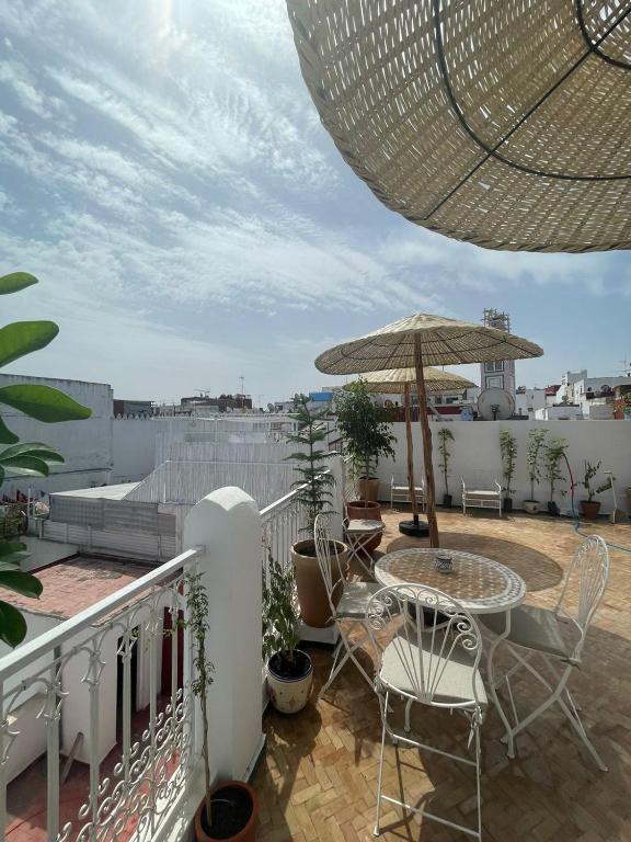 a balcony with a table and chairs and an umbrella at Riad SULTANA in Tangier