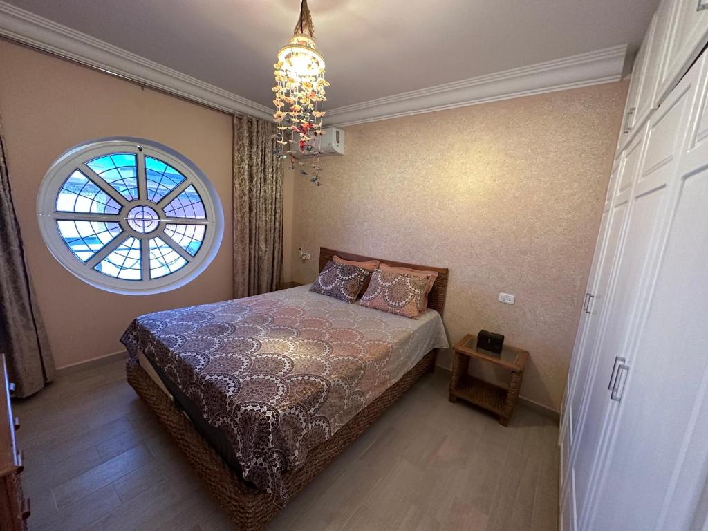 una camera con letto, finestra e lampadario a braccio di Villa Zembretta a El Haouaria