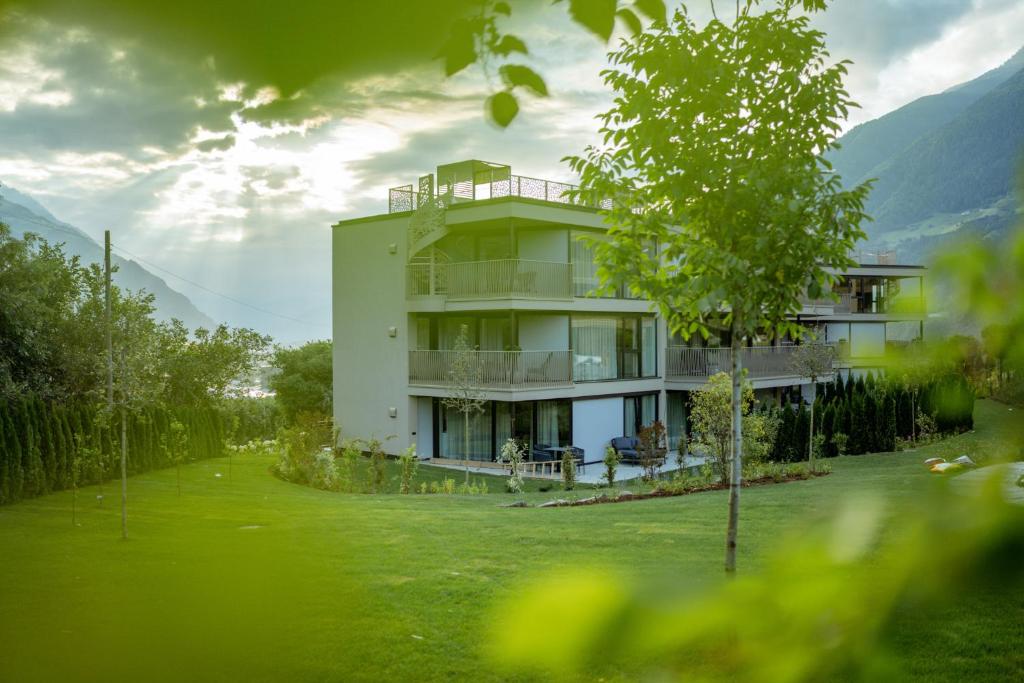 a house with a green yard in front of it at Boutique Hotel AMARIL in Kastelbell-Tschars