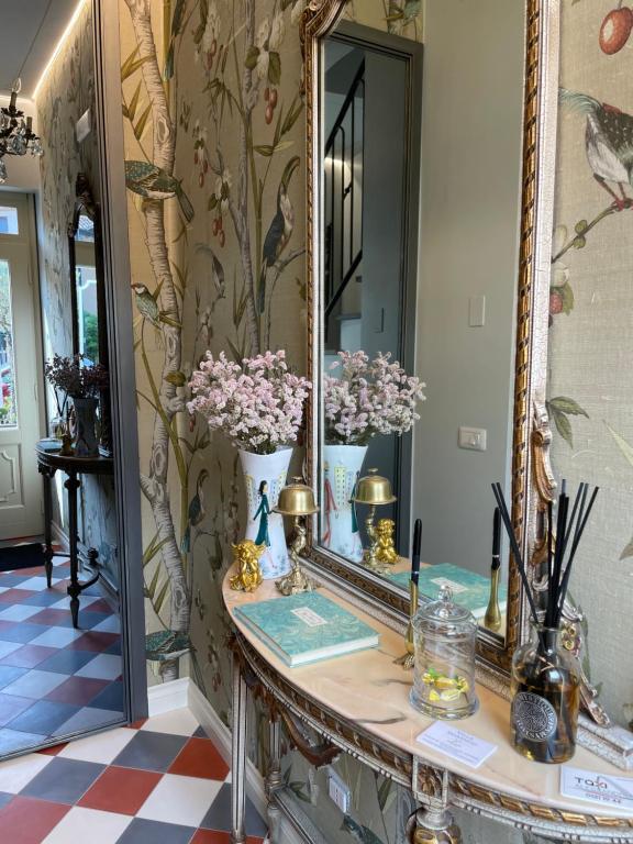 Villa Marengo Guest House في سبينيتّا: طاولة خلع الملابس مع الزهور في المرآة