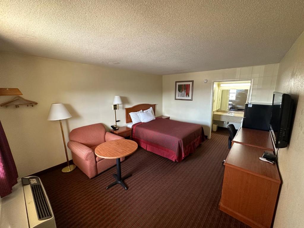 a hotel room with a bed and a chair and a television at Sunrise Extended Stay in Searcy