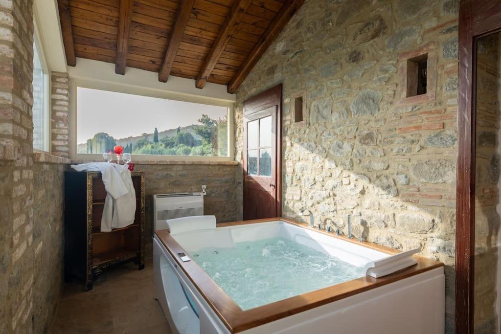 a large bathroom with a tub in a stone wall at Villetta Montalla in Cortona