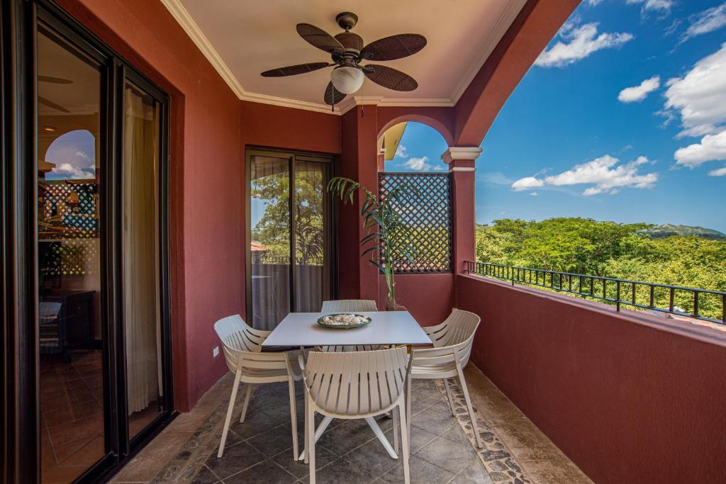 uma varanda com uma mesa e cadeiras e uma ventoinha de tecto em Boungainvillea 1203 Luxury Apartment - Reserva Conchal em Playa Conchal
