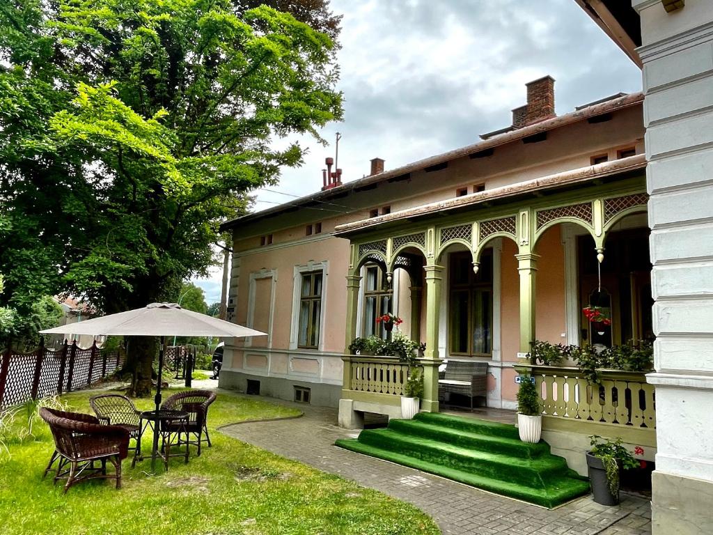 una casa antigua con sillas y una sombrilla en el patio en Willa Szwadron, en Łańcut