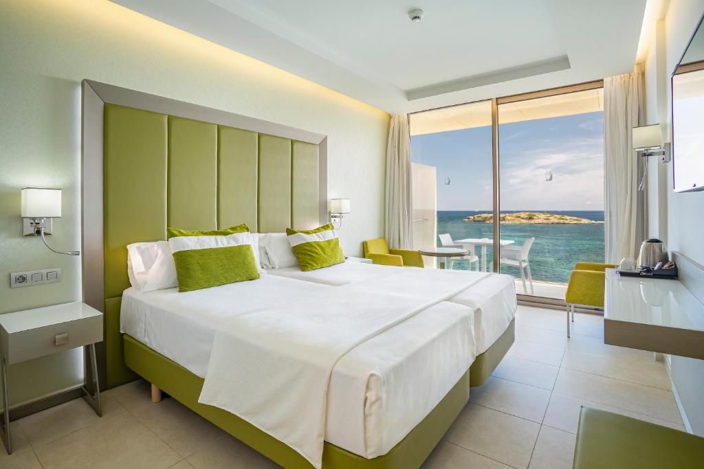 a bedroom with a large bed with a view of the ocean at Hotel Torre del Mar - Ibiza in Playa d'en Bossa