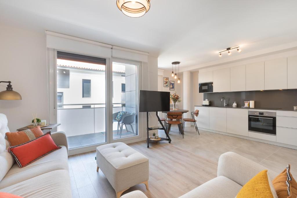 a living room with a white couch and a kitchen at Salakobeta - baskeyrentals in Lasarte