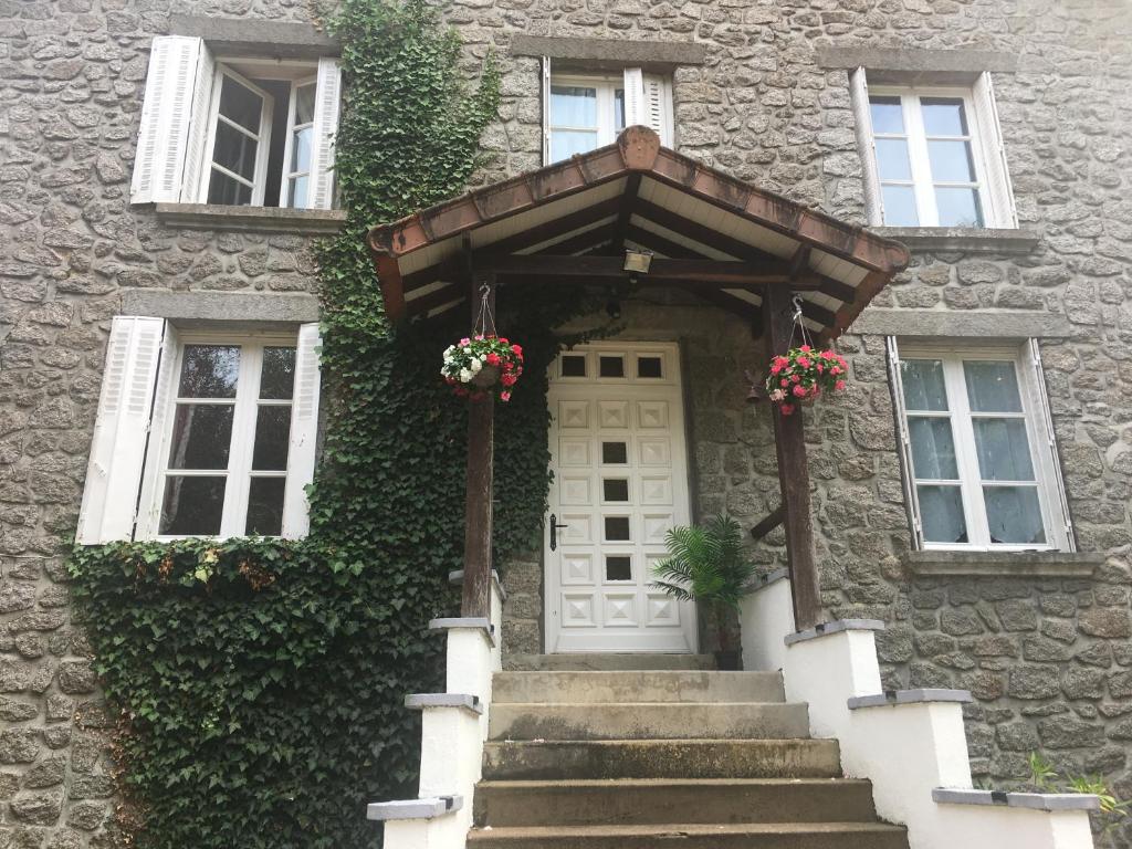 une maison en pierre avec une porte blanche ornée de fleurs dans l'établissement Stylish House near Lake and Beach at St Estephe, à Augignac
