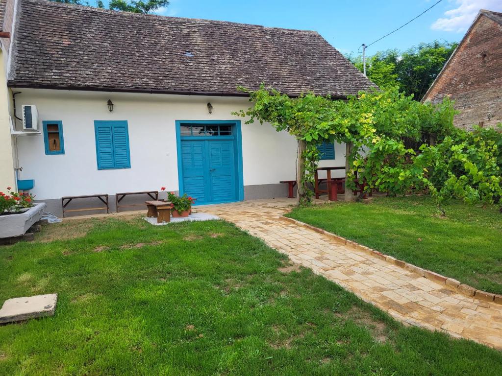 una casa con una puerta azul y un patio en Dézsavár Vendégház, en Majs