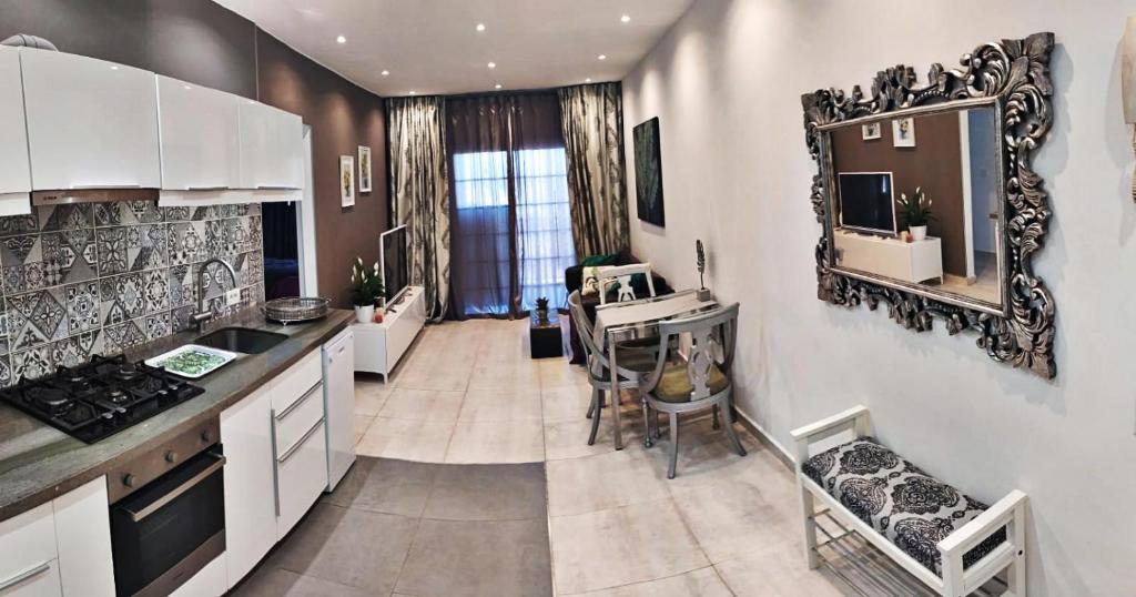 uma cozinha com armários brancos, uma mesa e um espelho em Cosy 2 bedroom near sea Costa del Silencio em Costa Del Silencio