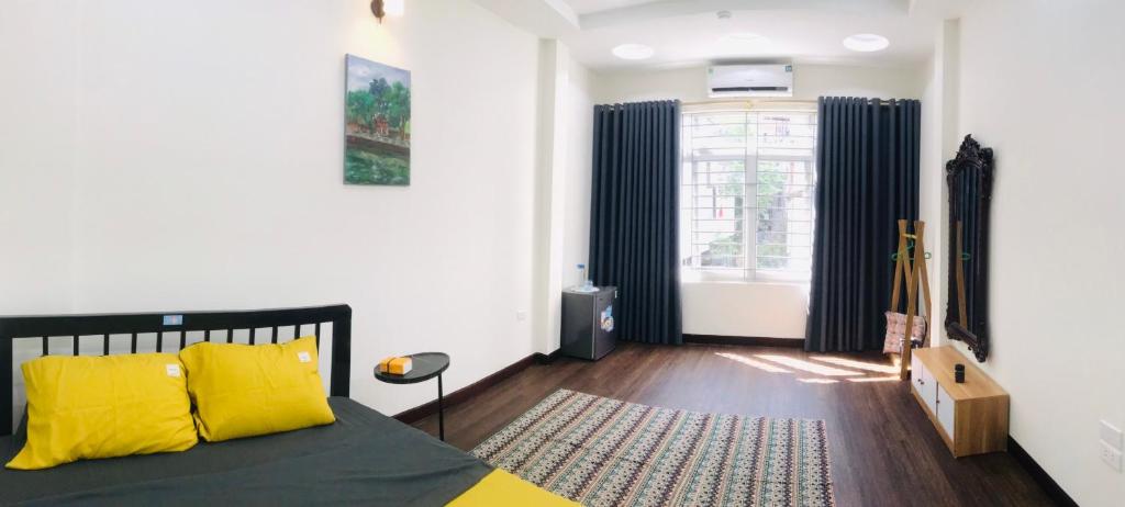 a bedroom with a bed with yellow pillows and a window at May's Cottage in Hanoi