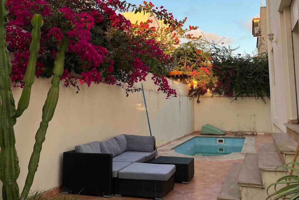 a patio with a couch and flowers on a wall at Villa Achakar in Tangier