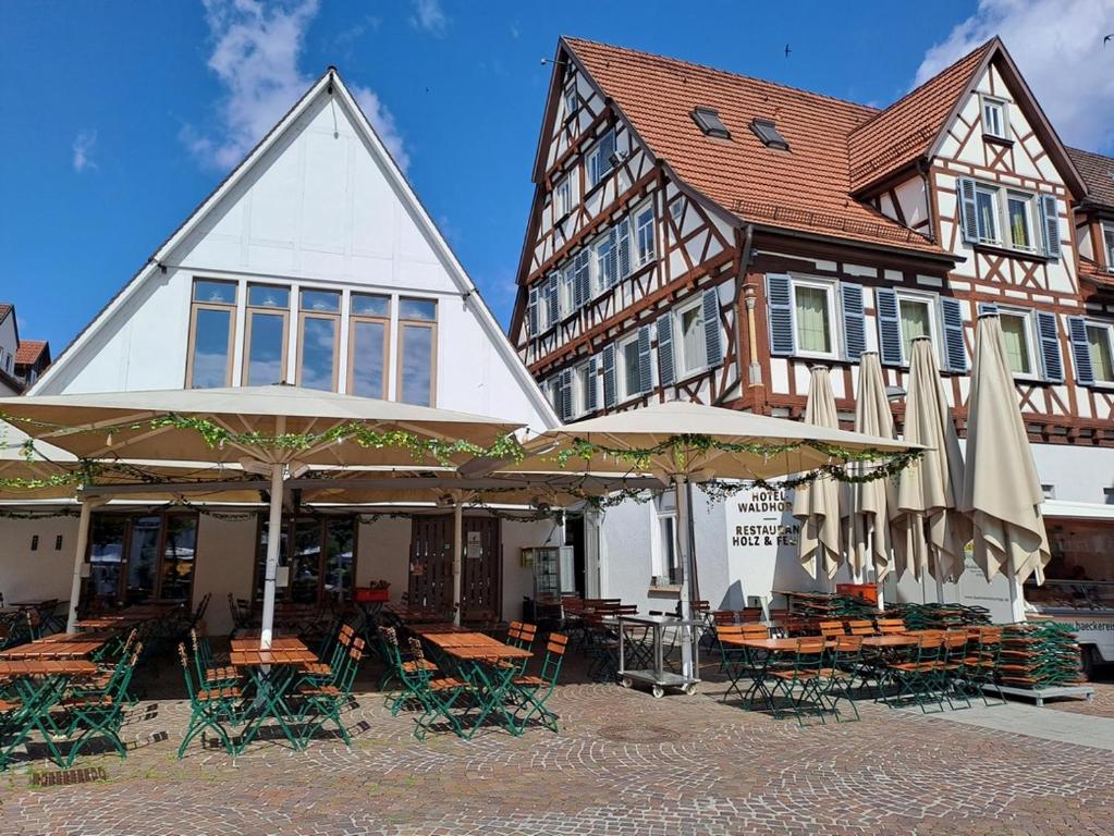 a building with tables and umbrellas in front of it at Stadthotel Waldhorn in Kirchheim unter Teck