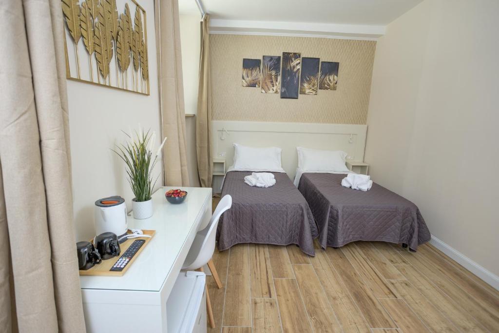 a small room with two beds and a desk at Sant'Erasmo Rooms in Rome