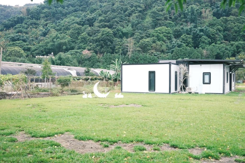 a white house in a field with cats in the yard at 埔里柴居民宿 in Puli