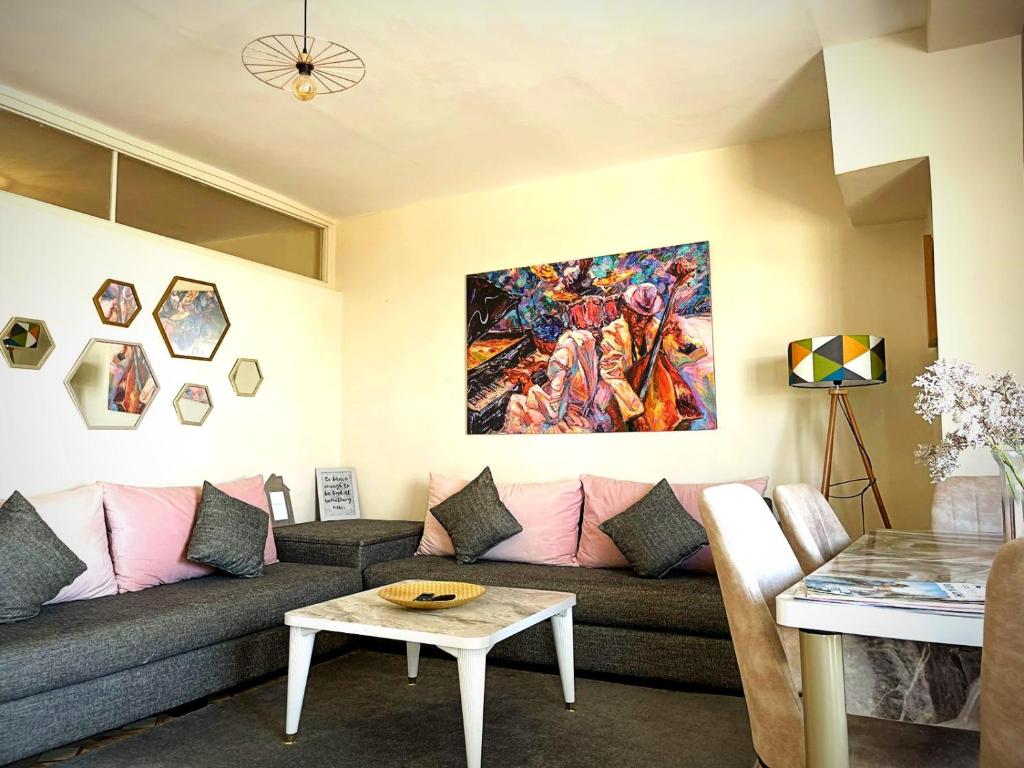 een woonkamer met een bank en een schilderij aan de muur bij Cosy appartement au super centre ville avec vue partielle sur le parc in Agadir
