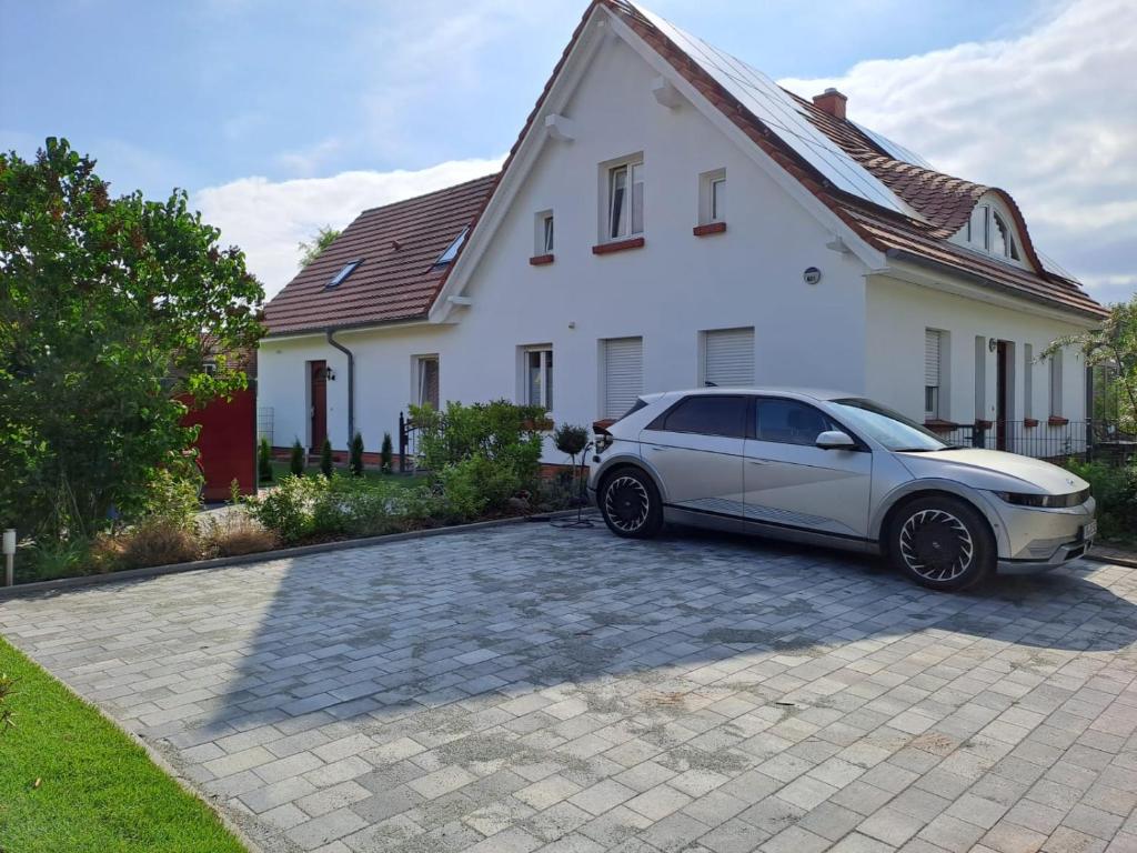 une voiture blanche garée devant une maison blanche dans l'établissement Ein Stück Glück, à Prerow