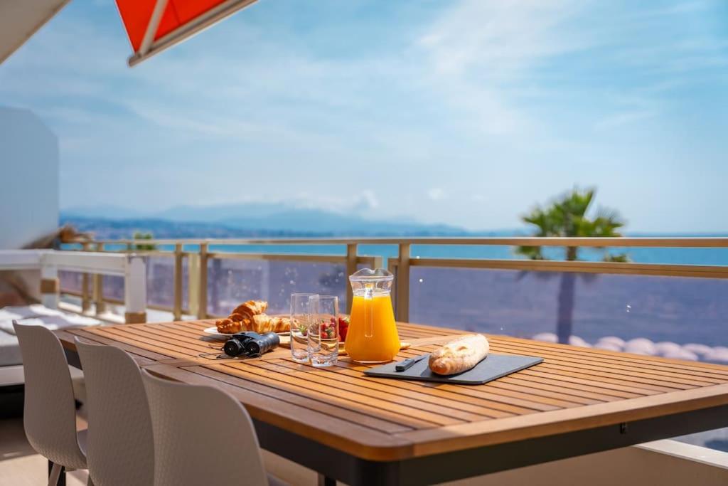 een houten tafel met een glas sinaasappelsap op een balkon bij Luxury flat on the Cote d'Azur in Villeneuve-Loubet