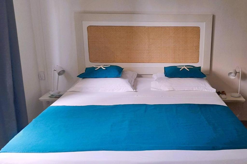 uma cama com lençóis azuis e brancos e almofadas azuis em MADRAS LODGE em Le Diamant