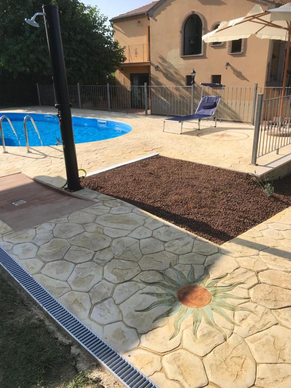 einen Pool mit einer Steinterrasse, auf der eine Blume gemalt ist in der Unterkunft Agriturismo cerquatonda B&B in Montalto delle Marche
