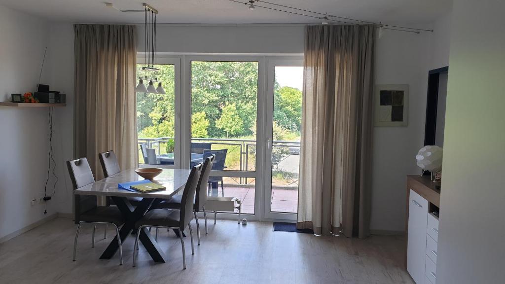 een eetkamer met een tafel en stoelen en een balkon bij Ferienwohnung Sonnenschein mit großem Balkon in Grömitz