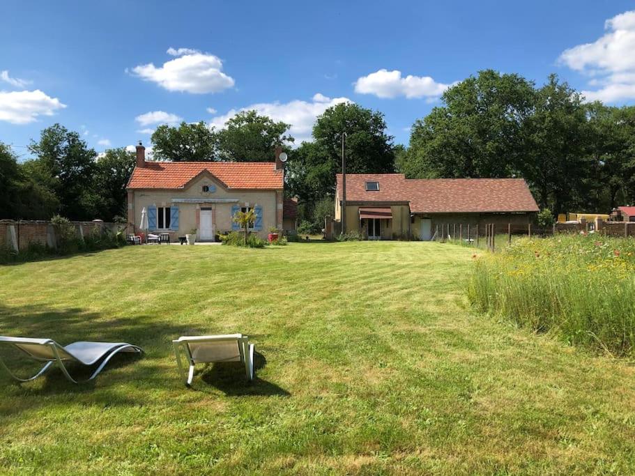 a yard with a house and a chair in the grass at Maison au milieu des bois et des animaux in Jouy-le-Potier