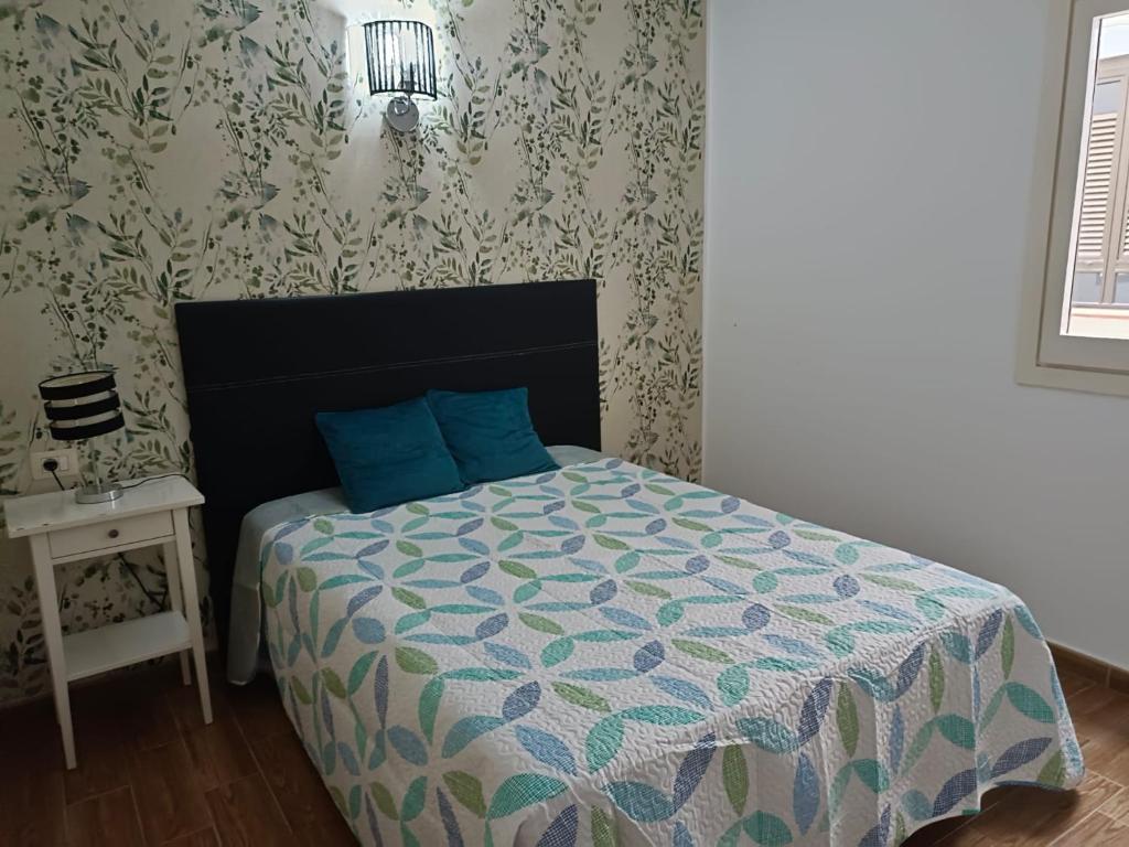 1 dormitorio con cama con edredón azul y mesa en Apartamento Victor Arico, en El Médano