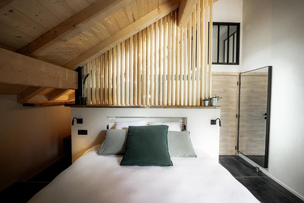 - une chambre avec un lit et un oreiller vert dans l'établissement La Loge de la Dolarde - Chambre Ouest, à Prémanon