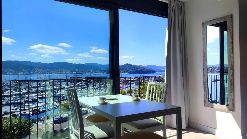 a room with a table and a view of a harbor at Apartamentos Dabarca Combarro in Combarro
