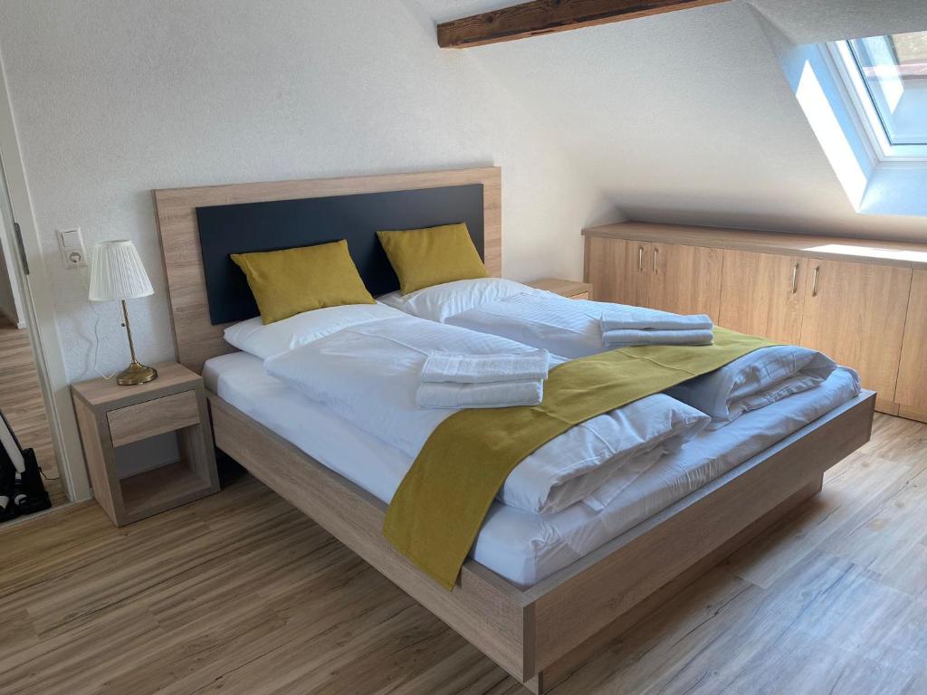 um quarto com uma cama grande com lençóis brancos e almofadas amarelas em Die Perle am Rhein em Waldshut-Tiengen