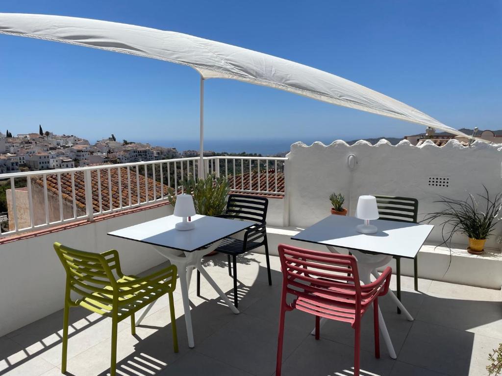 un patio con 2 mesas y sillas en un balcón en Los Nidos Apartments, Frigiliana, en Frigiliana