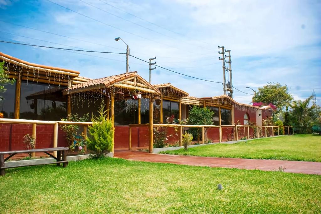 una casa con una valla en el césped en Bungalows Payancas de Tato en Barranca