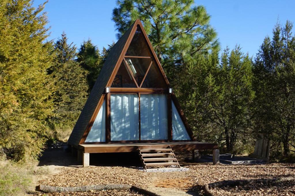 a small cabin with a glass roof in the woods at Cabaña A-Frame en La Estanzuela in Estanzuela