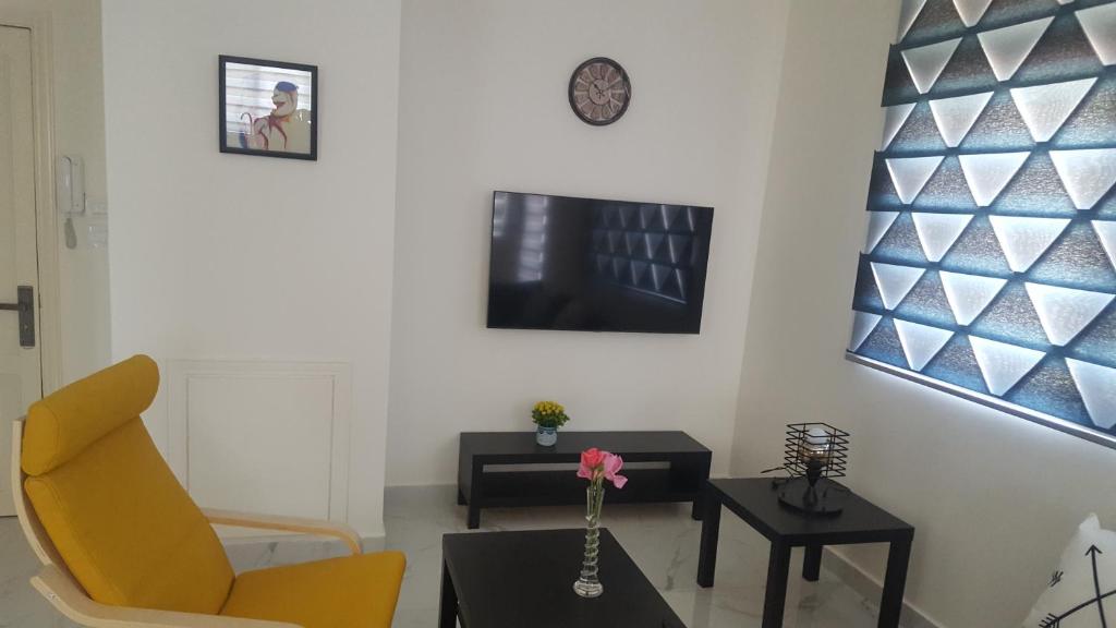 a living room with a yellow chair and a table at Aida's Home-Shmeisani central location near Abdali in Amman