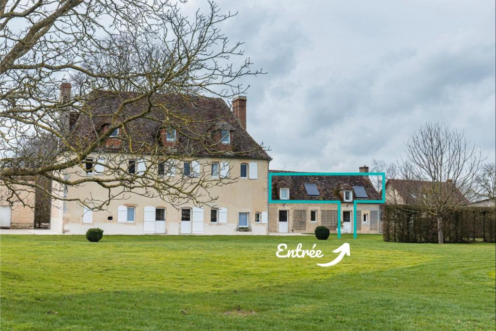 une grande maison sur un champ verdoyant avec un arbre dans l'établissement Bagatelle avec Jardin et Piscine Chauffée, à Biéville-en-Auge