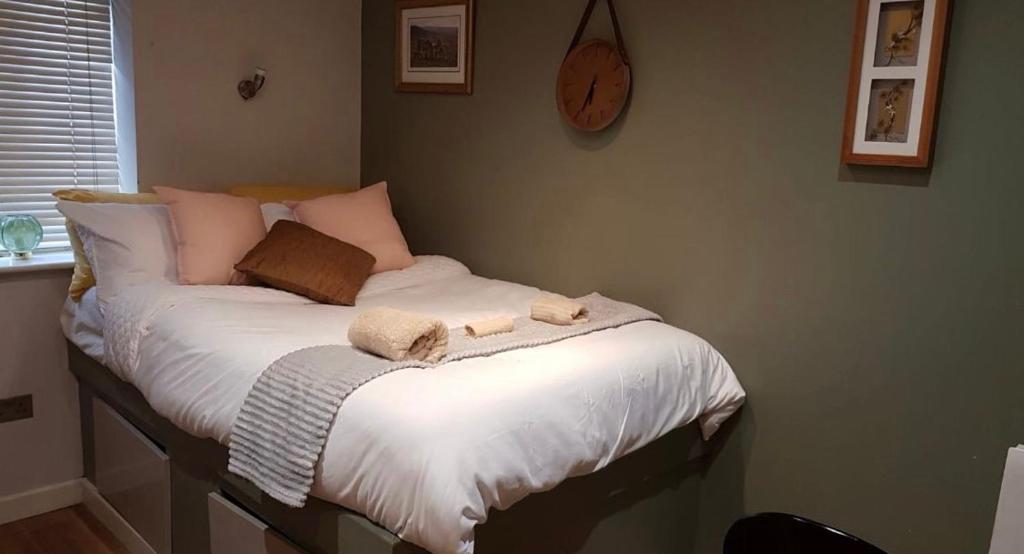 a bed with two towels and a clock on the wall at Affordable Flats - Derby City Centre in Derby