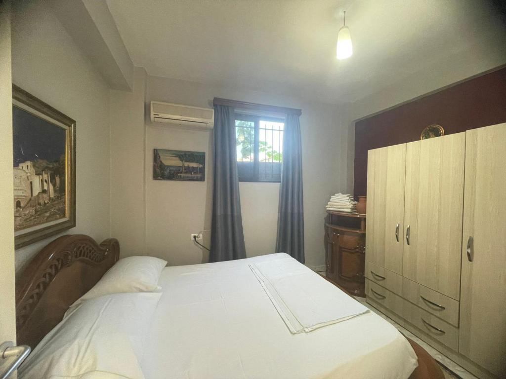 a bedroom with a white bed and a window at Flat in Tirana