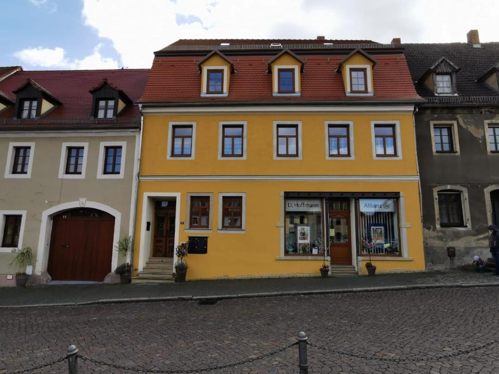 uma casa amarela com um telhado vermelho numa rua em Gästewohnung Fischer em Strehla
