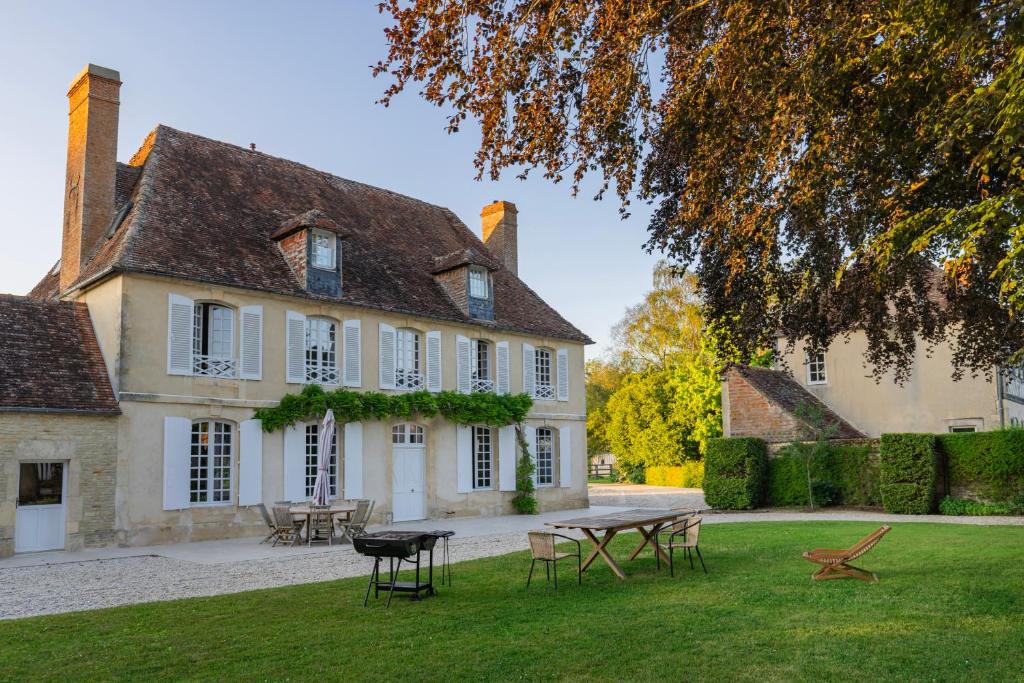 una casa grande con una mesa de picnic en el patio en Le Presbytère - demeure d'exception historique, en Biéville-en-Auge