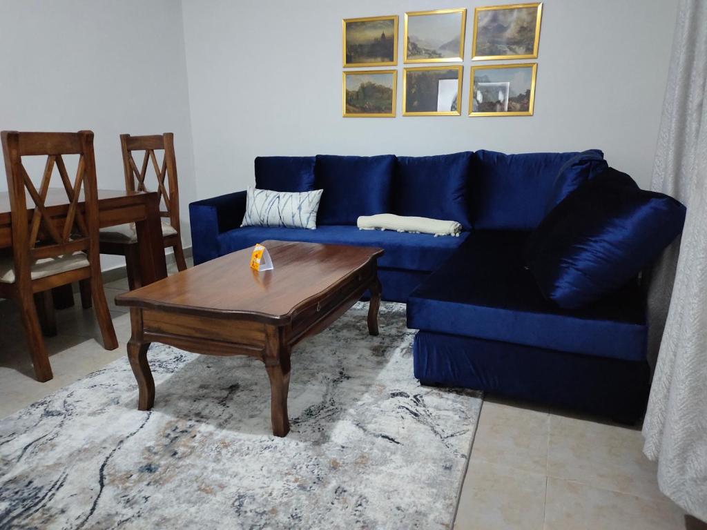 Zoe Homes Oak Villa Apartment 1 and 2 Bedroom 201 في Kericho: غرفة معيشة مع أريكة زرقاء وطاولة قهوة