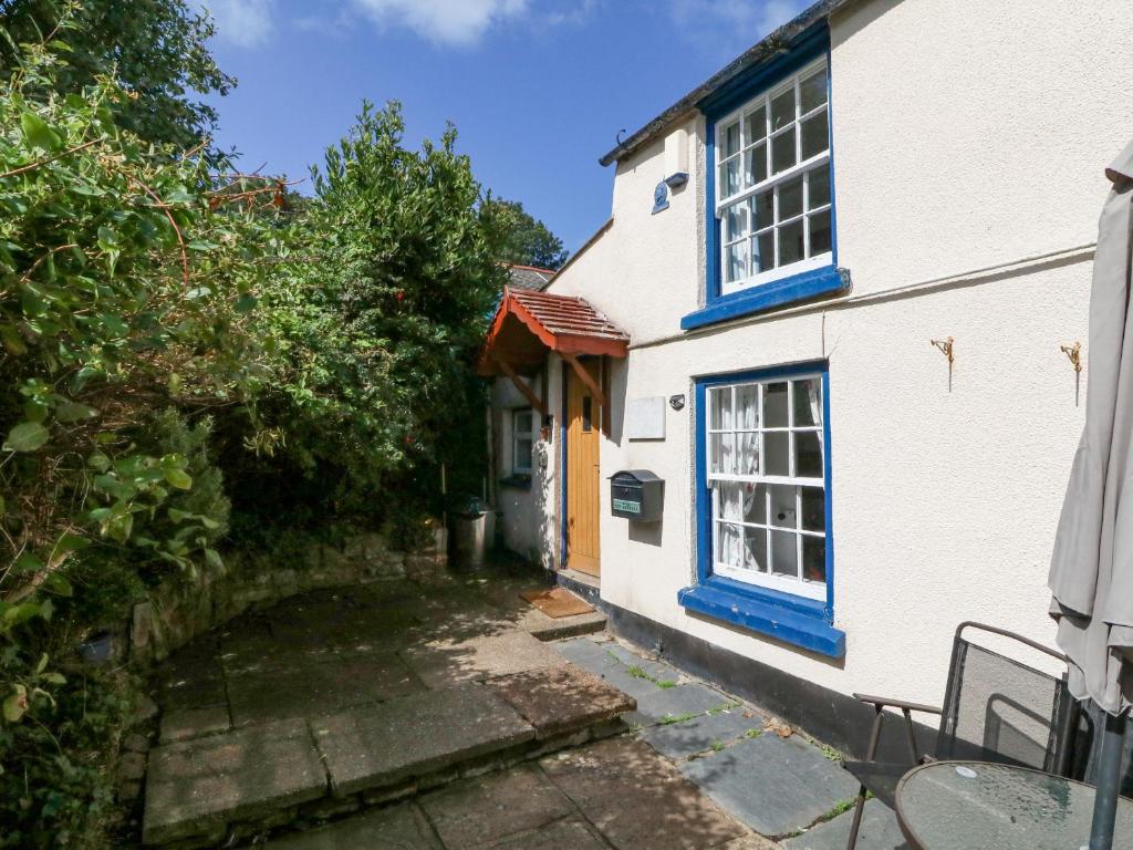 Casa blanca con ventanas azules y patio en The Retreat, en Bideford