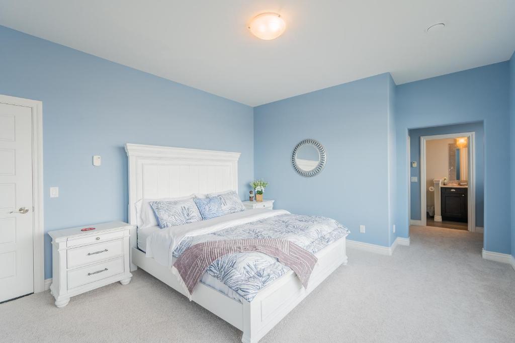 een slaapkamer met een wit bed en blauwe muren bij Cozy one bedroom with private bathroom in Kelowna in Kelowna