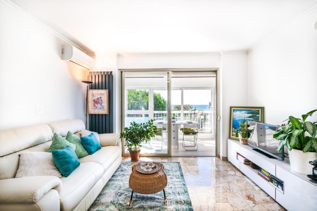 een woonkamer met een witte bank en een tv bij Résidence méditerranée - Beachfront - Sun and Seaview - Pool - Private Parking in Cagnes-sur-Mer