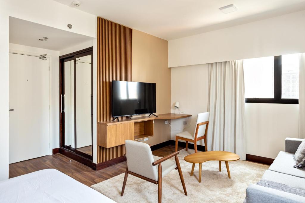 a hotel room with a television and a living room at Tabas - Melia Confort in São Paulo